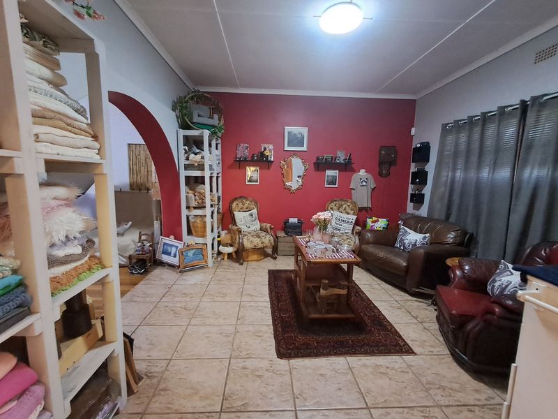 A living room featuring tiled flooring and an arched entryway leading to an adjacent space, with a prominent red accent wall.