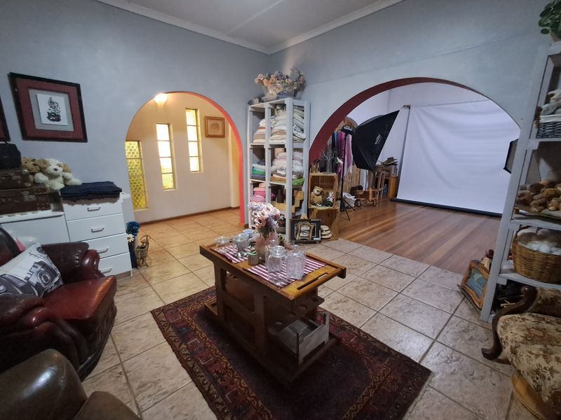 A living area featuring distinctive arched doorways, tiled flooring, and a transition to a secondary space with hardwood floors and decorative windows.