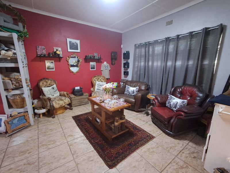 A living room featuring tiled flooring, a coved ceiling, and a bold red accent wall, providing a functional space for relaxation.