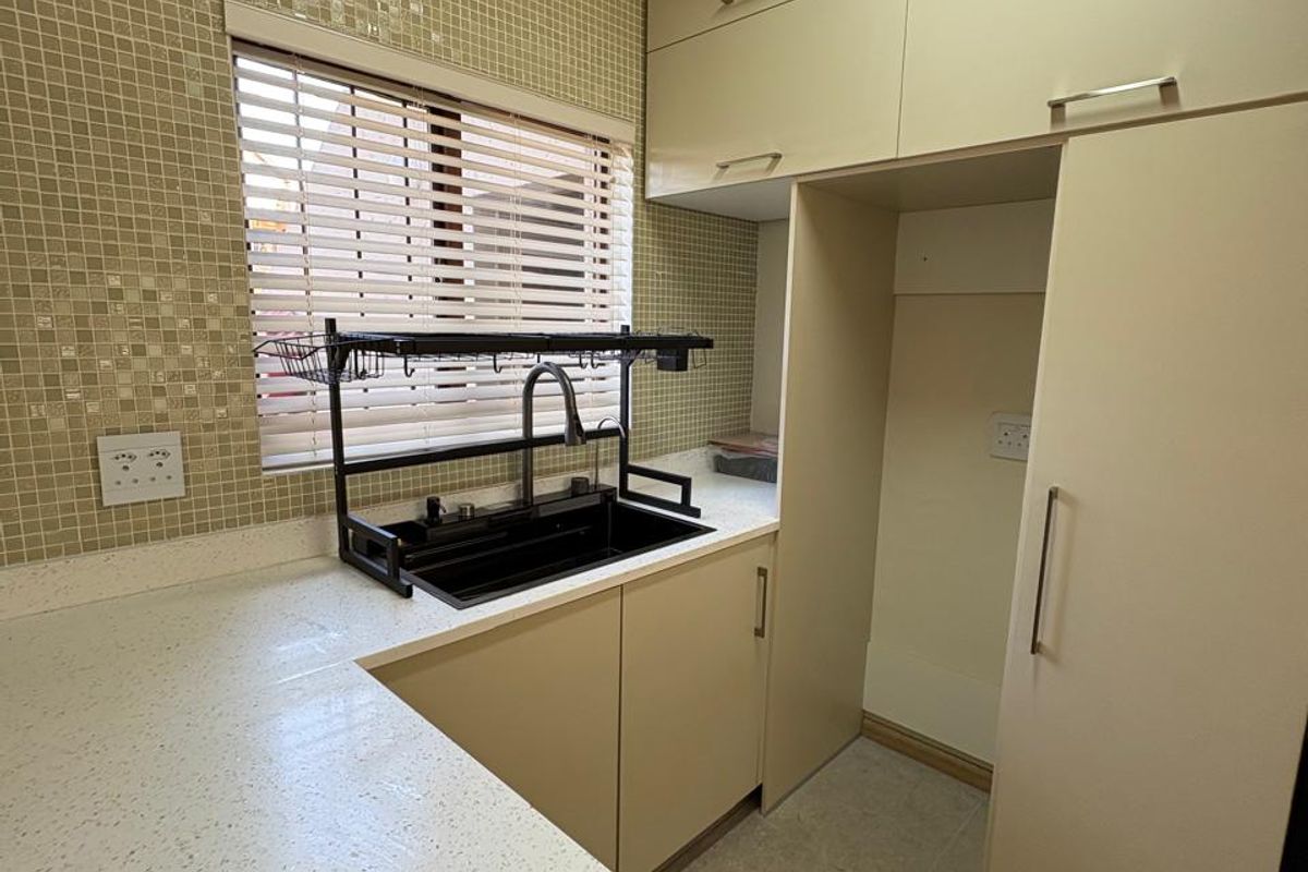 A functional kitchen featuring built-in cabinetry, stone-look countertops, a tiled backsplash, and dedicated space for integrated appliances.