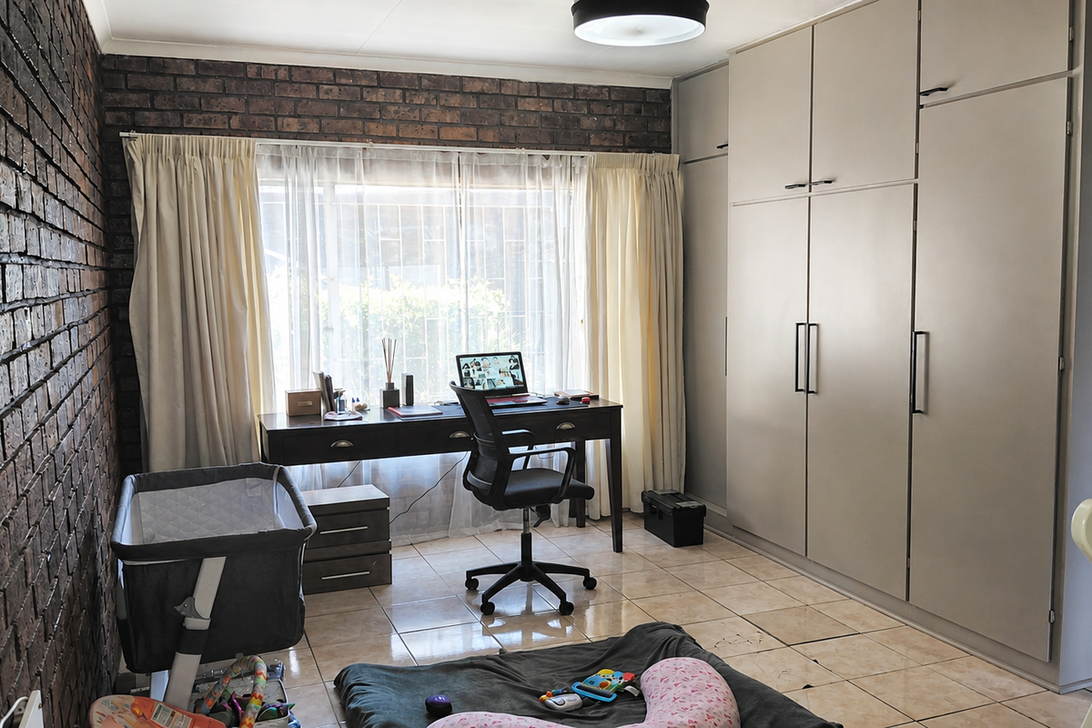 A bedroom featuring an exposed brick feature wall, tiled flooring, and extensive built-in cupboard storage.