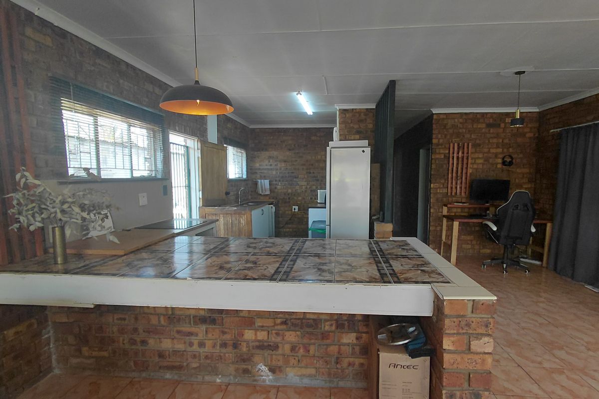 Open plan living and kitchen area featuring exposed brick walls, tiled breakfast bar, and tiled flooring throughout.