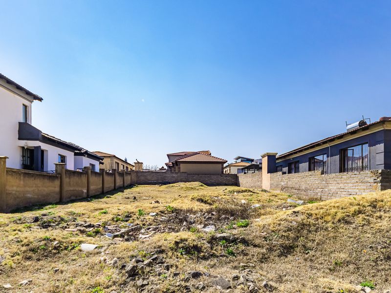 A vacant residential plot enclosed by perimeter boundary walls, situated within an established neighborhood setting.