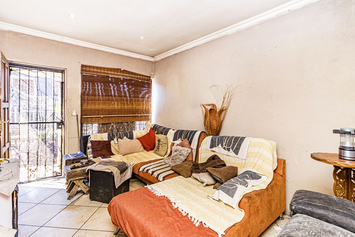 A living room featuring tiled flooring, recessed lighting, and a security gate leading to the exterior.