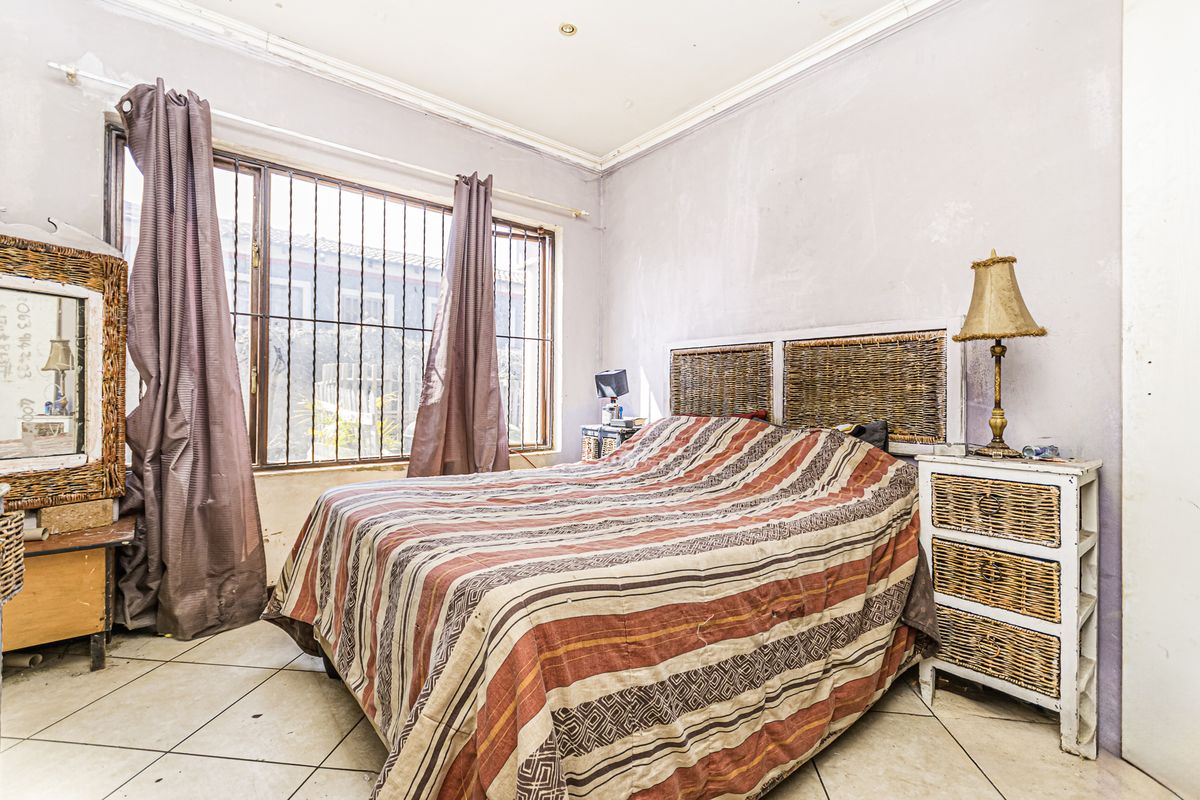A bedroom featuring tiled flooring, security bars on the window, and recessed lighting, currently requiring cosmetic updates to the wall finishes.