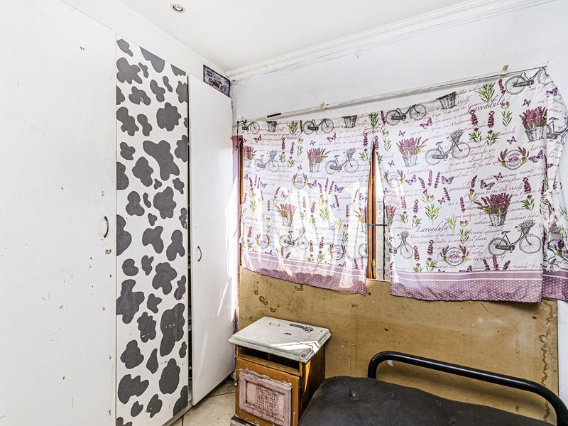 A bedroom featuring a built-in wardrobe and recessed lighting, currently requiring cosmetic updates and wall repairs to restore its condition.