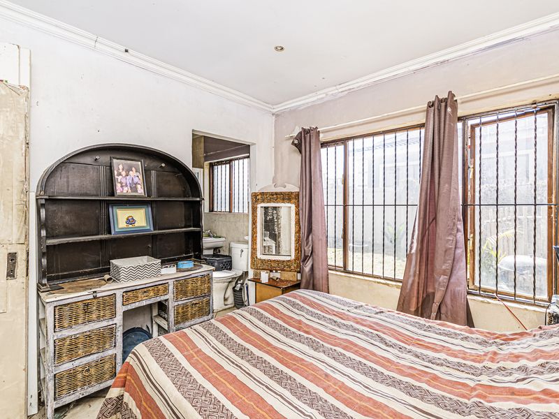 A bedroom featuring security bars on the windows and visible wear on the wall finishes, requiring cosmetic updates.