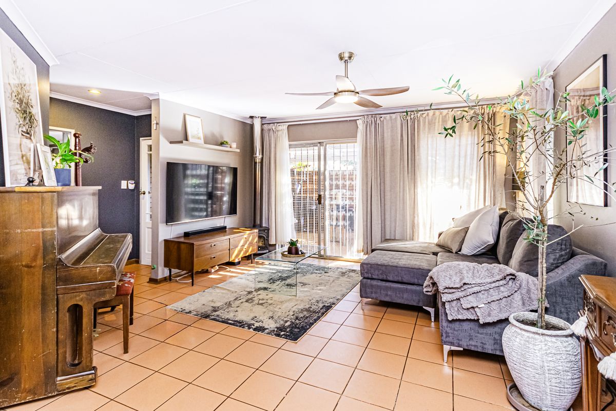 A comfortable living room featuring tiled flooring, a wood-burning stove, and a ceiling fan, with direct access to the outdoor area via sliding glass doors.