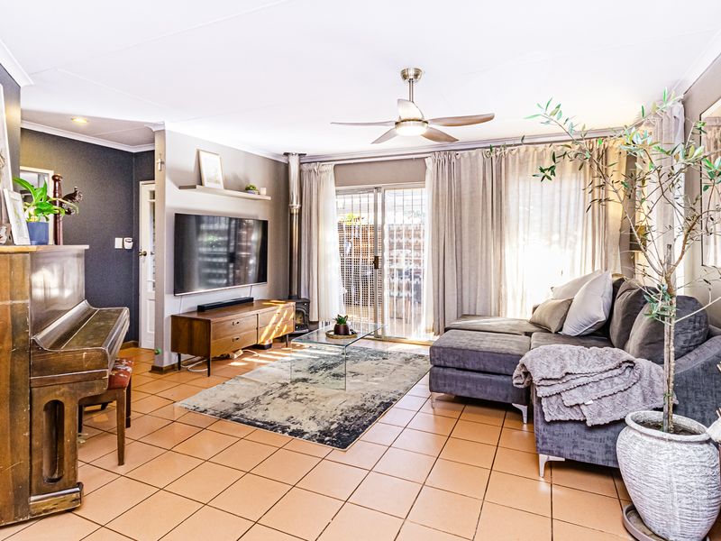 A comfortable living room featuring tiled flooring, a wood-burning stove, and a ceiling fan, with direct access to the outdoor area via sliding glass doors.