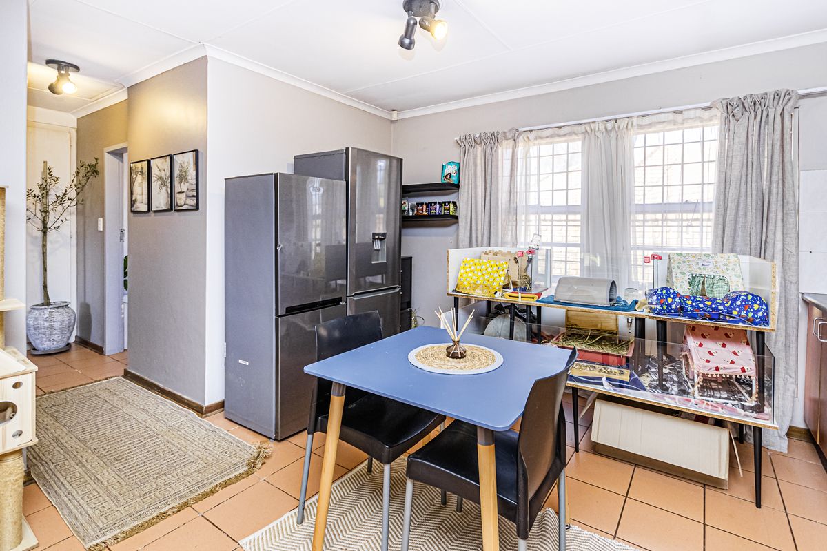 A functional kitchen area featuring tiled flooring, ceiling spotlights, and a window with security bars, providing a practical space for daily use.