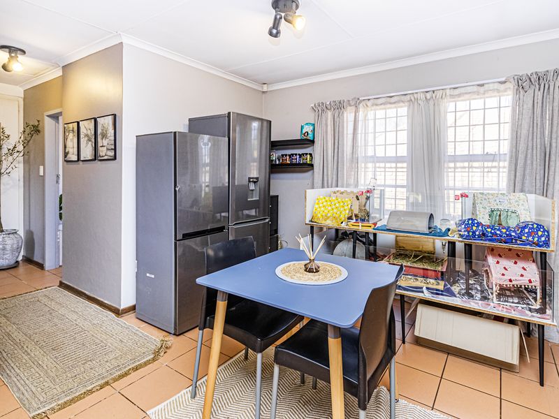 A functional kitchen area featuring tiled flooring, ceiling spotlights, and a window with security bars, providing a practical space for daily use.