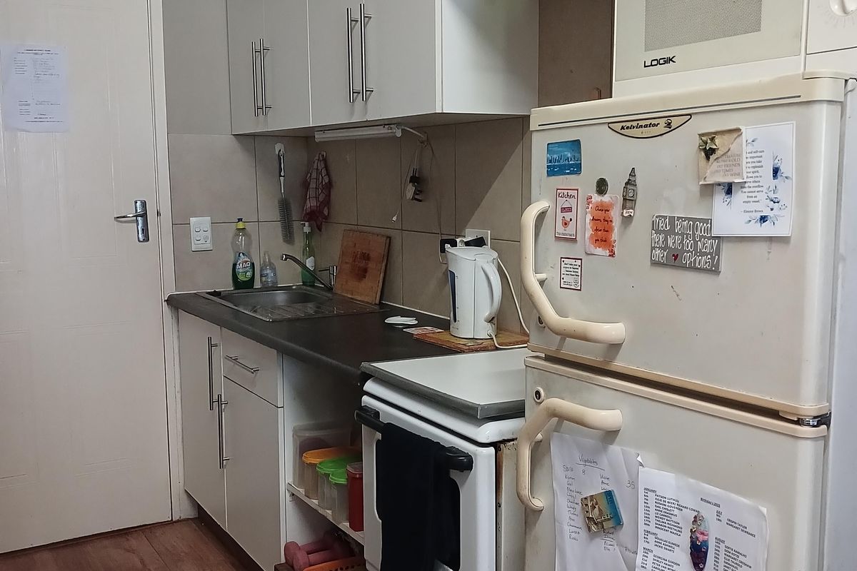 A compact kitchen featuring white cabinetry, a stainless steel sink, tiled backsplash, and a freestanding stove, providing functional storage and preparation space.