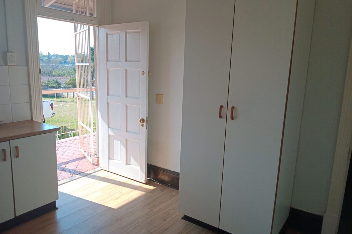 A bright bedroom featuring laminate flooring, a built-in wardrobe, and direct access to an outdoor patio area through a panel door.
