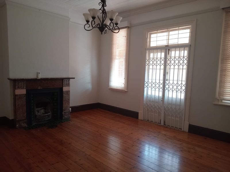 Spacious living room featuring original timber flooring, a classic fireplace, and secure access to the exterior.