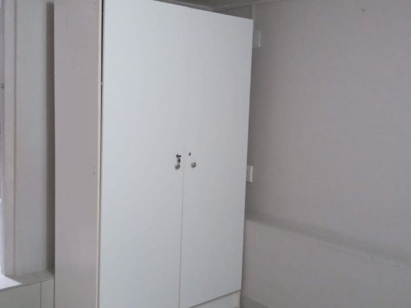 A bedroom featuring tiled flooring and a built-in wardrobe, with an adjoining en-suite bathroom visible.