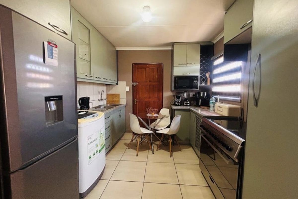 A functional kitchen featuring fitted cabinetry, tiled flooring, a built-in oven, and a double sink with a tiled backsplash.