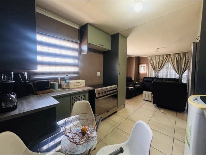 Open-plan kitchen and living area featuring tiled flooring, built-in cabinetry, and a freestanding oven, creating a functional and connected living space.