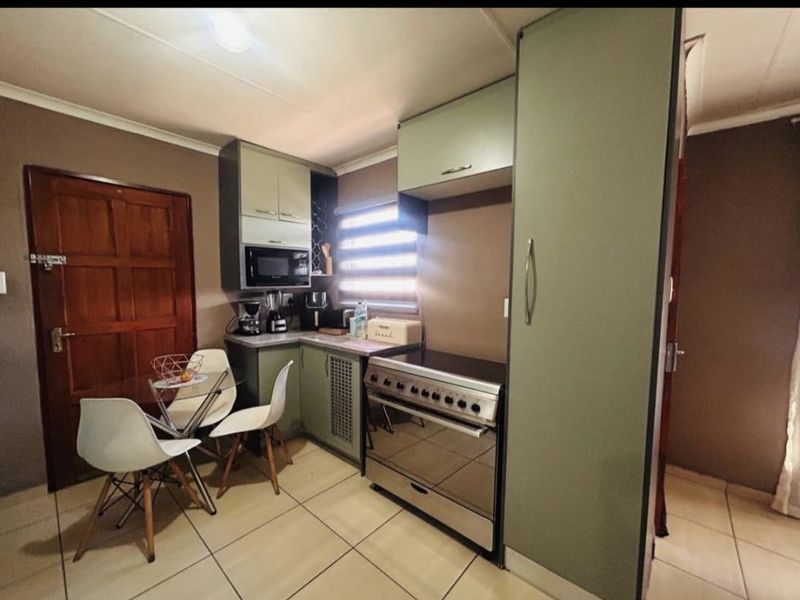 Compact kitchen featuring sage green cabinetry, tiled flooring, and a freestanding stove, providing a functional and efficient cooking space.
