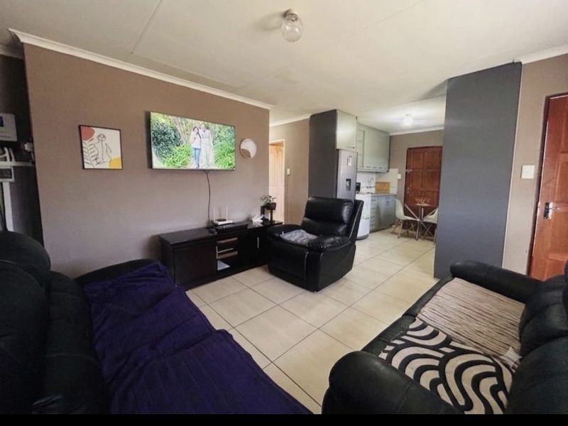Open-plan living area featuring tiled flooring and a connected kitchen space with built-in cabinetry.