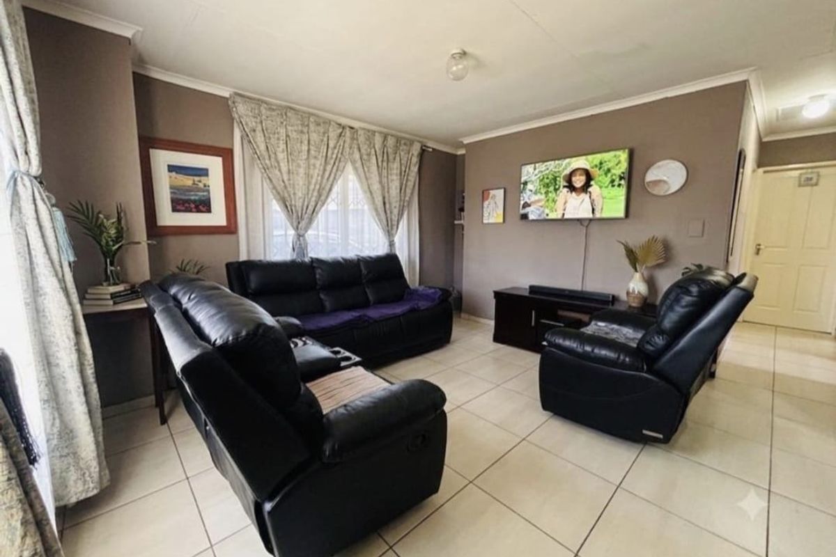 A comfortable living room featuring neutral tiled flooring and coved ceilings, providing a functional and well-maintained space for relaxation.