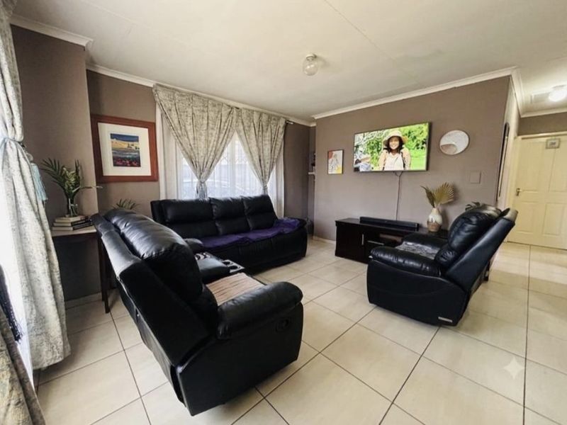 A comfortable living room featuring neutral tiled flooring and coved ceilings, providing a functional and well-maintained space for relaxation.