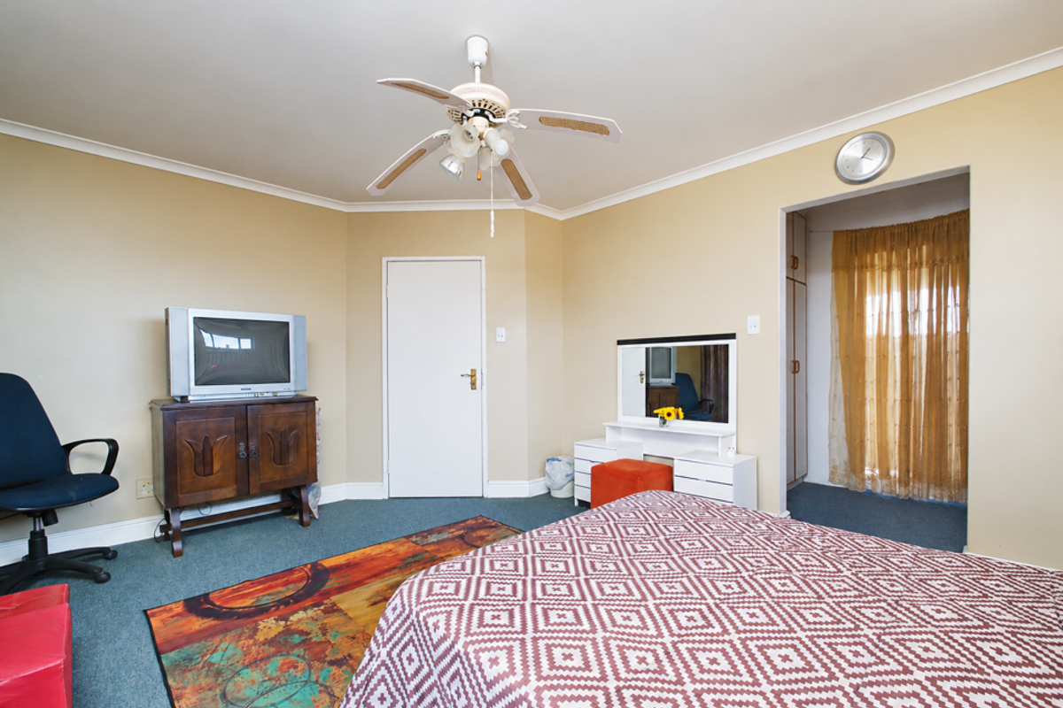 A bedroom featuring a ceiling fan, neutral wall finishes, and an adjoining walk-in closet area with built-in storage.