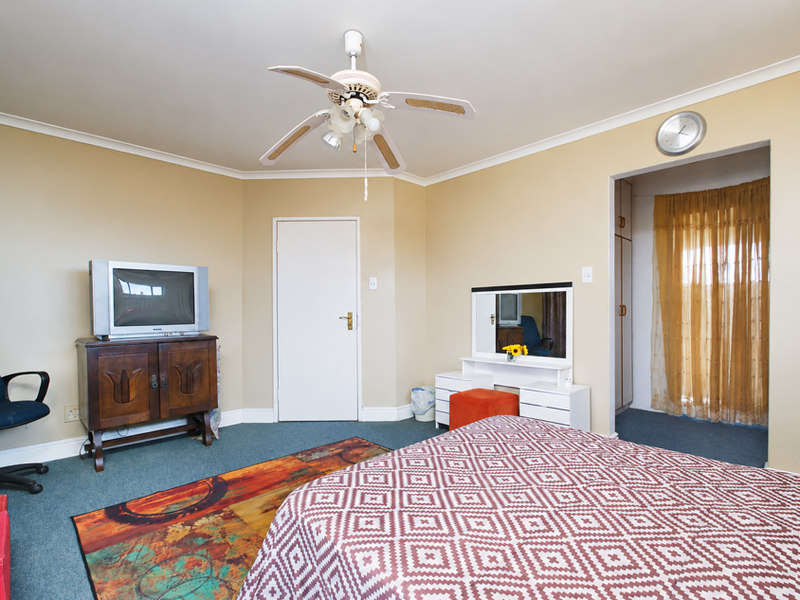 A bedroom featuring a ceiling fan, neutral wall finishes, and an adjoining walk-in closet area with built-in storage.