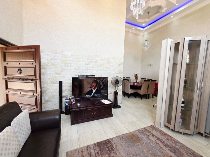 Open plan living and dining area featuring high coffered ceilings with recessed lighting, stone veneer accent wall, and polished tile flooring.
