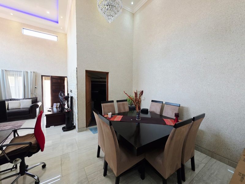 Spacious dining area featuring high ceilings, elegant crystal chandelier, recessed lighting, and polished porcelain tile flooring.