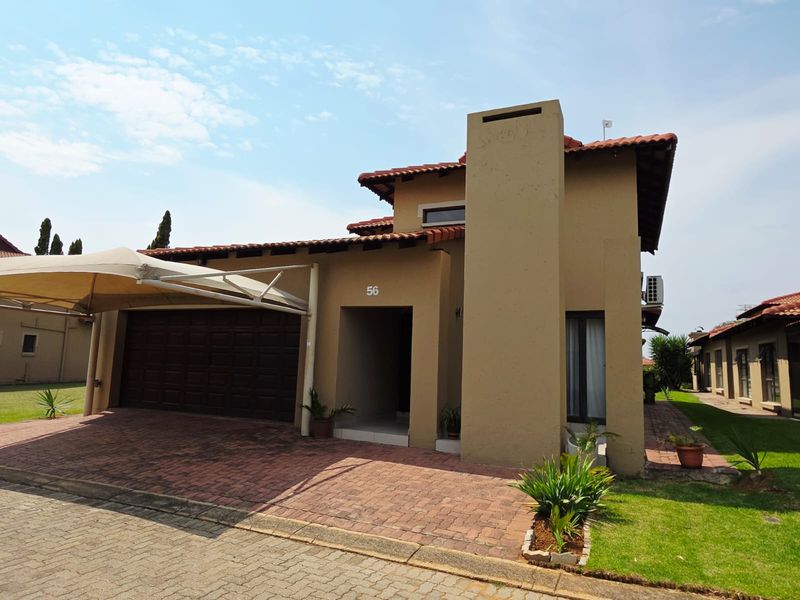 Front elevation of a residential house featuring a brick driveway, attached garage with shade sail, and a prominent chimney stack.