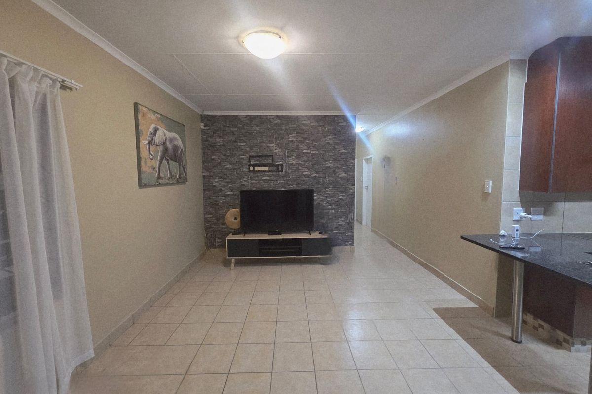 Open plan living area featuring a stone veneer accent wall, tiled flooring, and a granite breakfast bar connecting to the kitchen space.