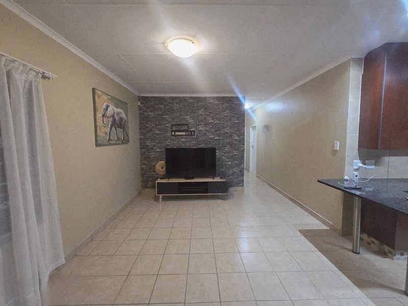 Open plan living area featuring a stone veneer accent wall, tiled flooring, and a granite breakfast bar connecting to the kitchen space.