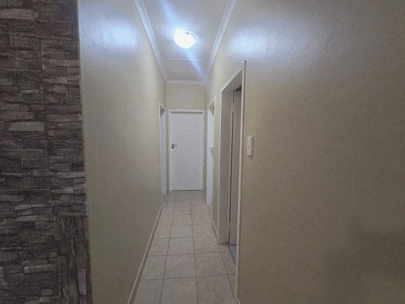 A clean, neutral-toned hallway featuring tiled flooring and a decorative stone veneer accent wall.