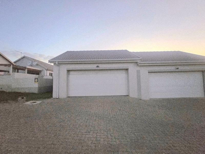 A well-maintained double garage with white sectional doors and a paved driveway, featuring a clean exterior facade.
