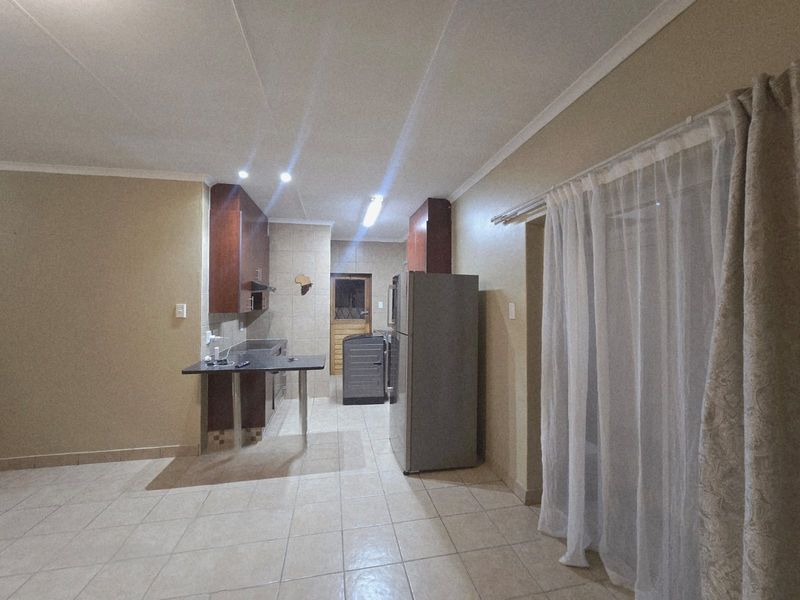 Open plan kitchen area featuring tiled flooring, built-in cabinetry, and a breakfast counter, providing a functional space for cooking and casual dining.
