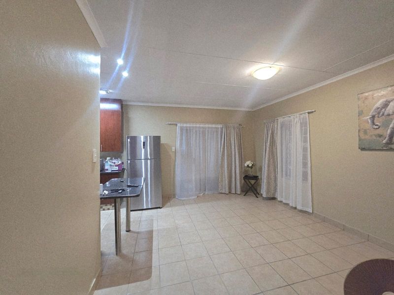 Open plan living and kitchen area featuring tiled flooring, a breakfast counter, and built-in cabinetry.