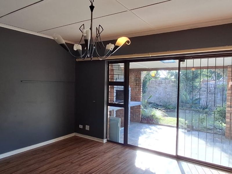 Spacious living room featuring laminate flooring, dark accent walls, and large sliding glass doors providing direct access to the outdoor patio area.