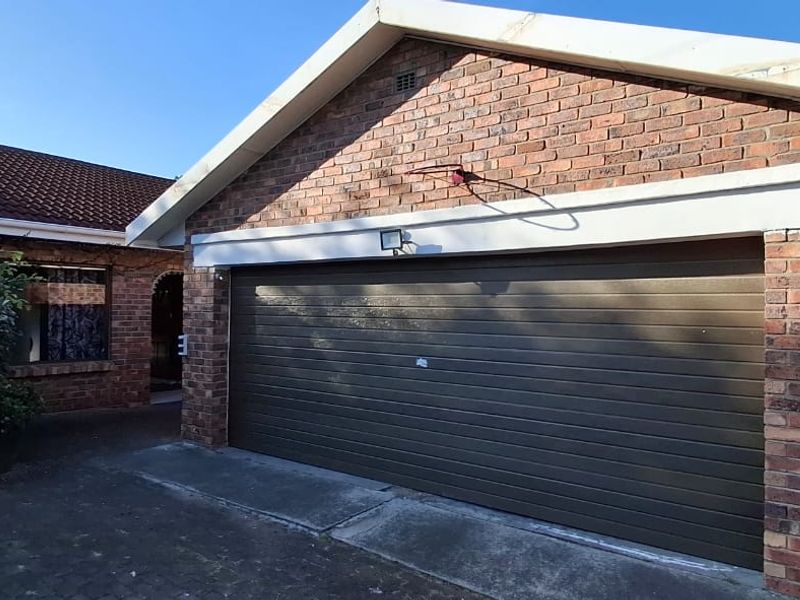Exterior view of a brick-faced garage with a sectional door and paved driveway access.