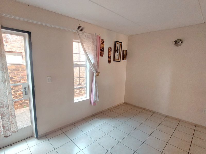 A vacant living area featuring tiled flooring, a single-pane window, and direct access to an exterior space.