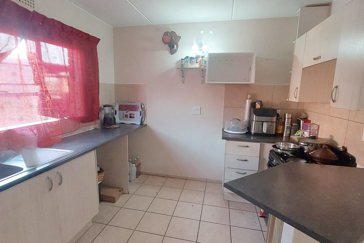 A functional kitchen featuring laminate cabinetry, tiled flooring, and a tiled splashback, offering a practical layout for daily meal preparation.