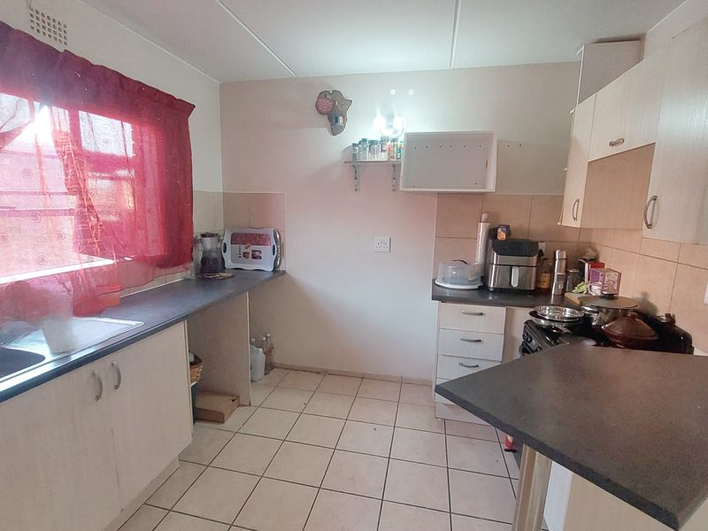 A functional kitchen featuring laminate cabinetry, tiled flooring, and a tiled splashback, offering a practical layout for daily meal preparation.