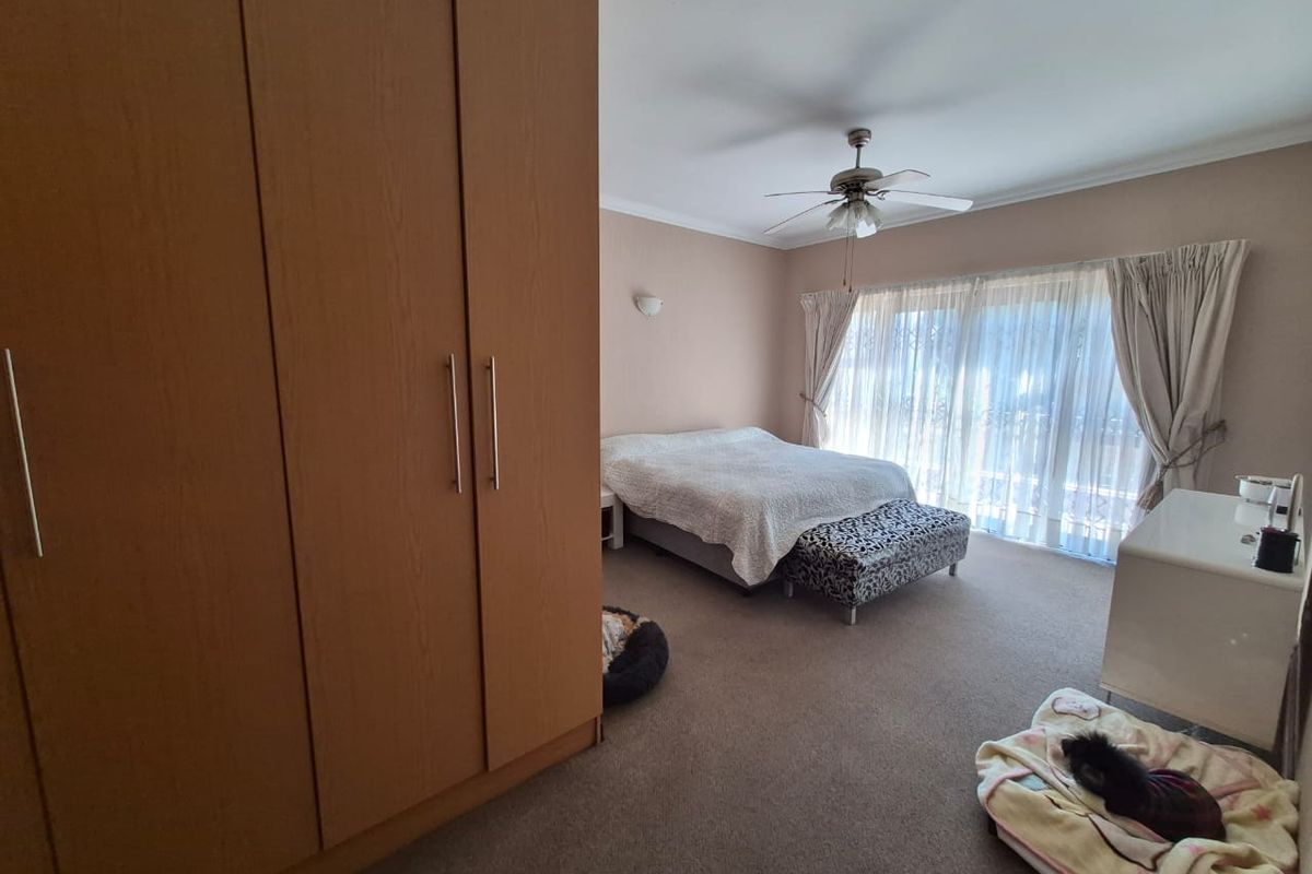 Spacious bedroom featuring a large built-in wardrobe, ceiling fan, and sliding glass doors that provide ample natural light.
