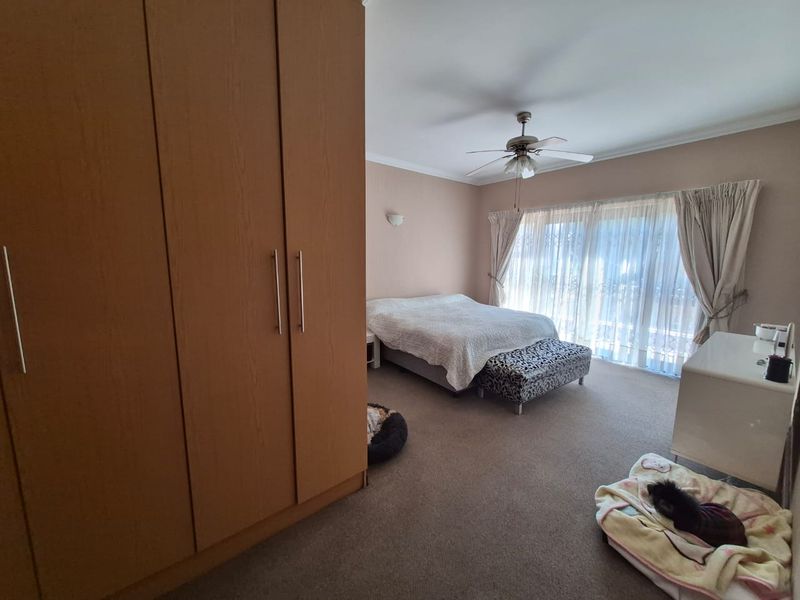 Spacious bedroom featuring a large built-in wardrobe, ceiling fan, and sliding glass doors that provide ample natural light.