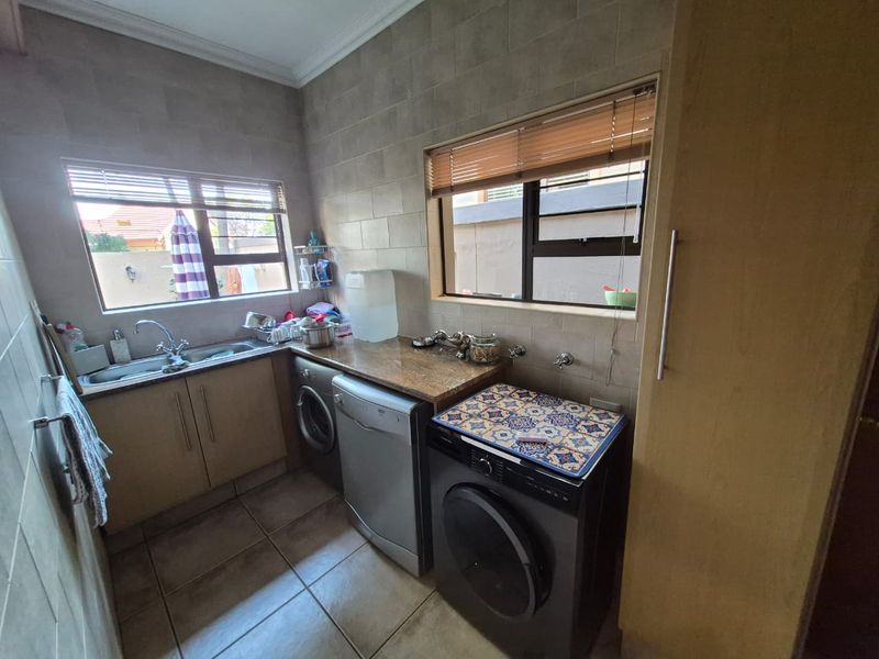 Functional laundry room featuring tiled walls, granite countertops, built-in cabinetry, and dedicated plumbing connections for appliances.