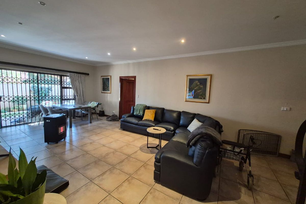 Spacious living area featuring neutral ceramic floor tiles, recessed lighting, and large sliding glass doors with security gates leading to the exterior.