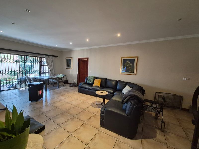 Spacious living area featuring neutral ceramic floor tiles, recessed lighting, and large sliding glass doors with security gates leading to the exterior.