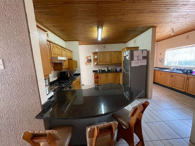 Spacious kitchen featuring wooden cabinetry, granite countertops, a breakfast bar, and a timber ceiling, offering a functional layout with ample storage space.