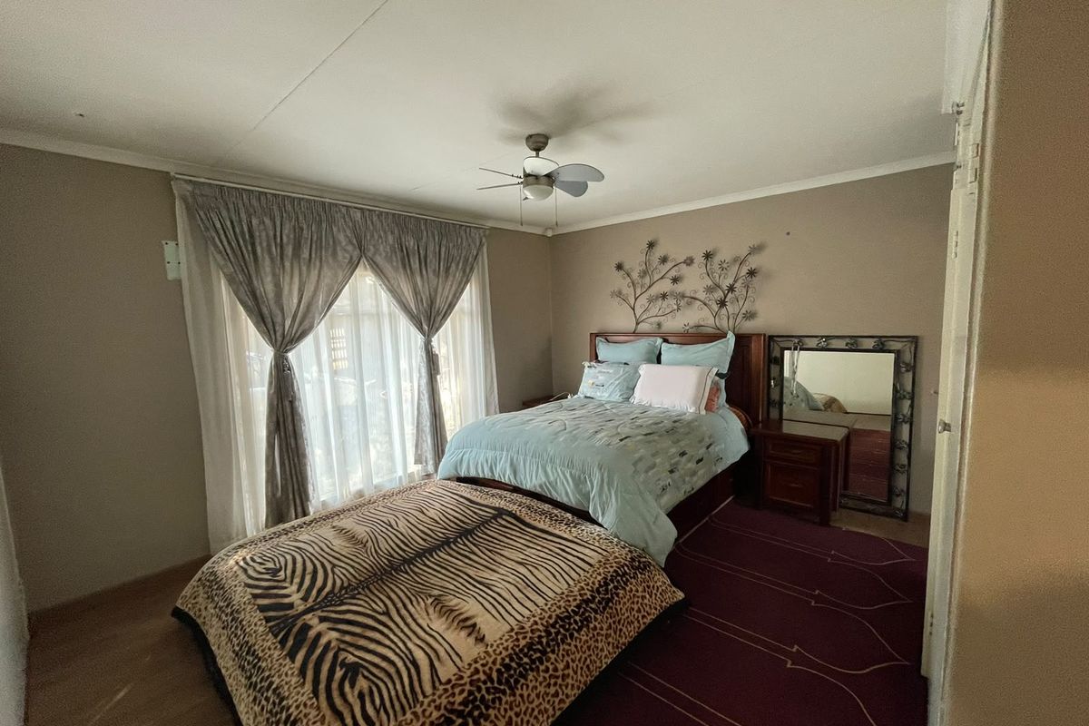 A standard bedroom featuring a ceiling fan and neutral wall tones, offering a functional space with potential for modern updates.