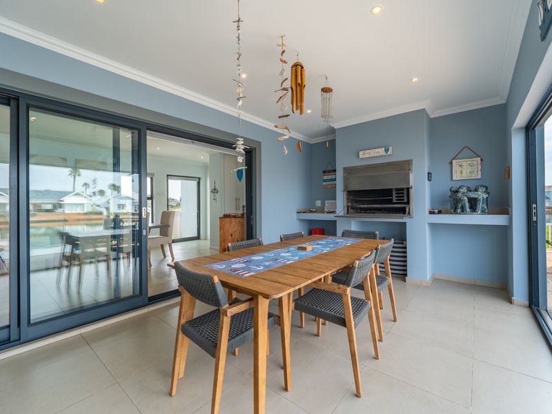 Covered patio area featuring a built-in braai, tiled flooring, and large sliding glass doors providing seamless indoor-outdoor flow.