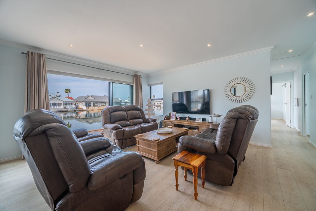 Spacious living room featuring light laminate flooring, recessed downlights, and large sliding glass doors offering scenic water views.